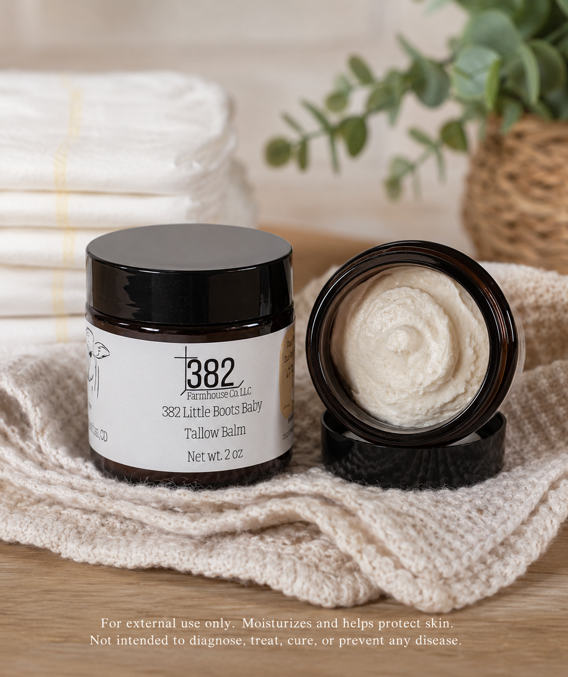 A jar of 382 Restorative Labs Little Boots Baby Tallow Balm shown with its lid off, revealing the cream-colored balm inside. The amber glass jar has a black lid and a white label.